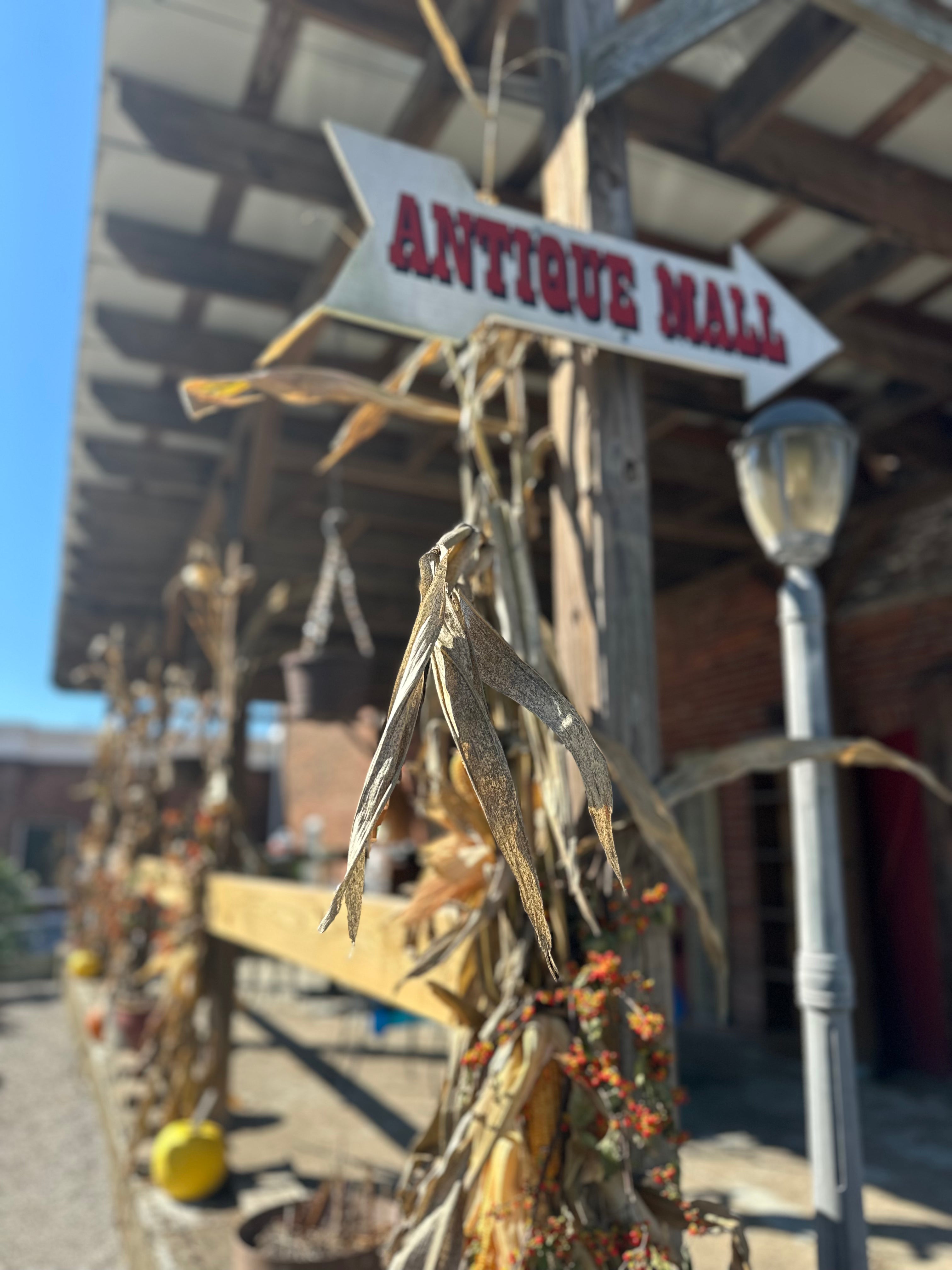 Decorative corn stalks with an 'Antique Mall' sign in the background.